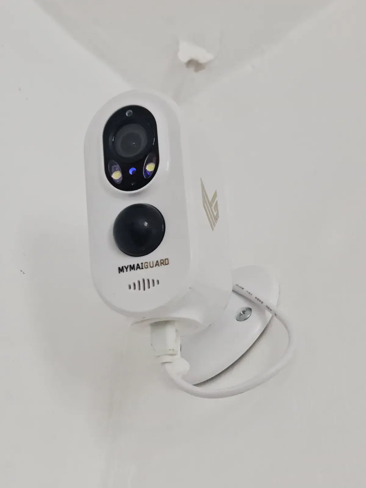 A small white MYMAiGUARD indoor WiFi camera mounted high on a wall
