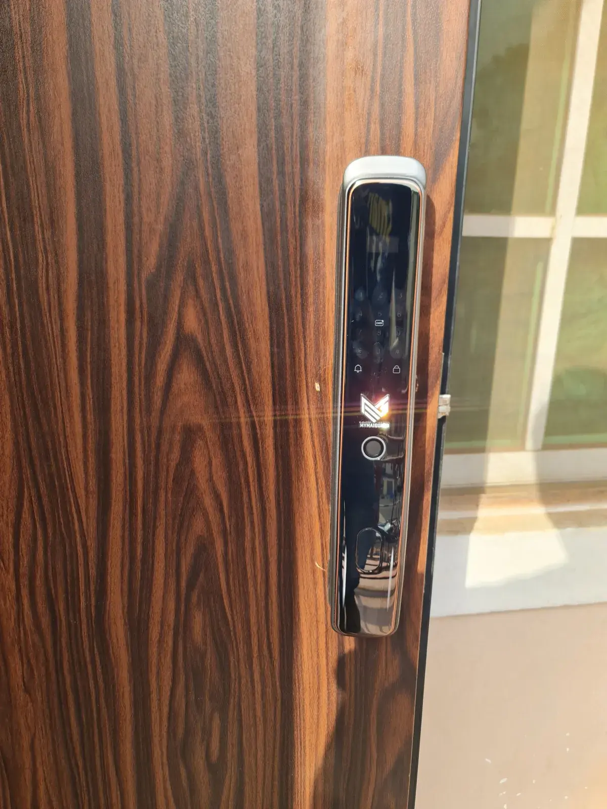 A MYMAiGUARD smart lock with keypad, card reader and fingerprint sensor fitted on a wood-finish front door