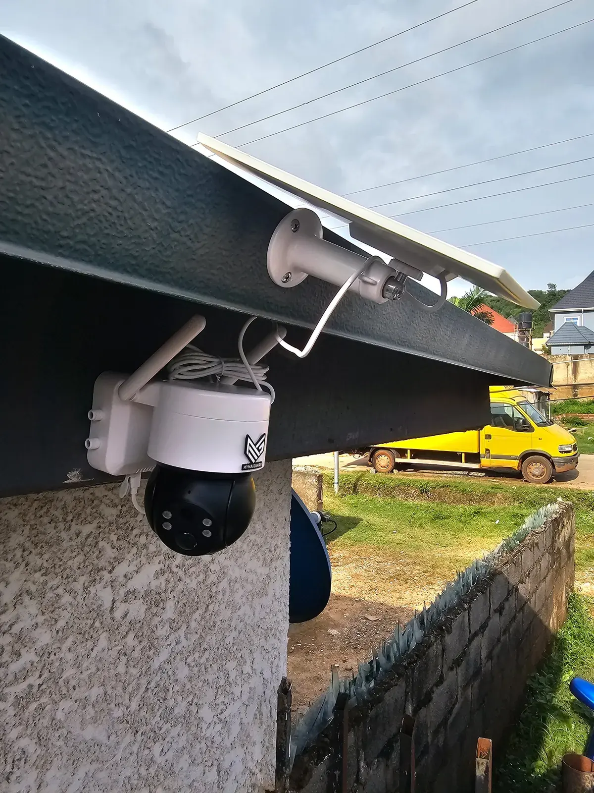 A MYMAiGUARD solar pan-and-tilt camera mounted under a roof edge with its solar panel above it
